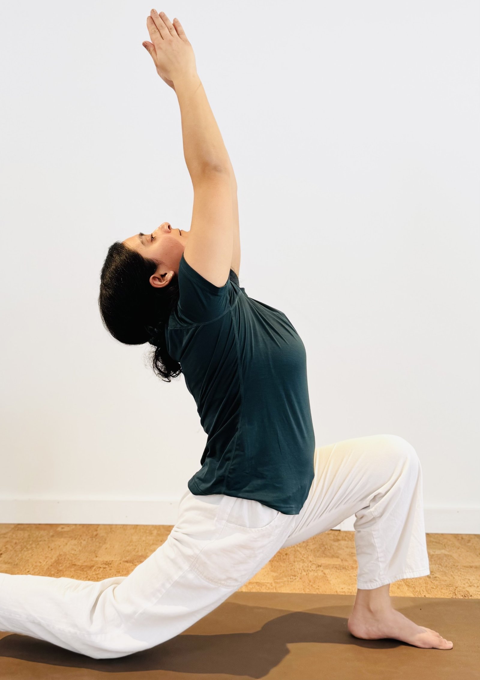Purnima in a low lunge with arms raised