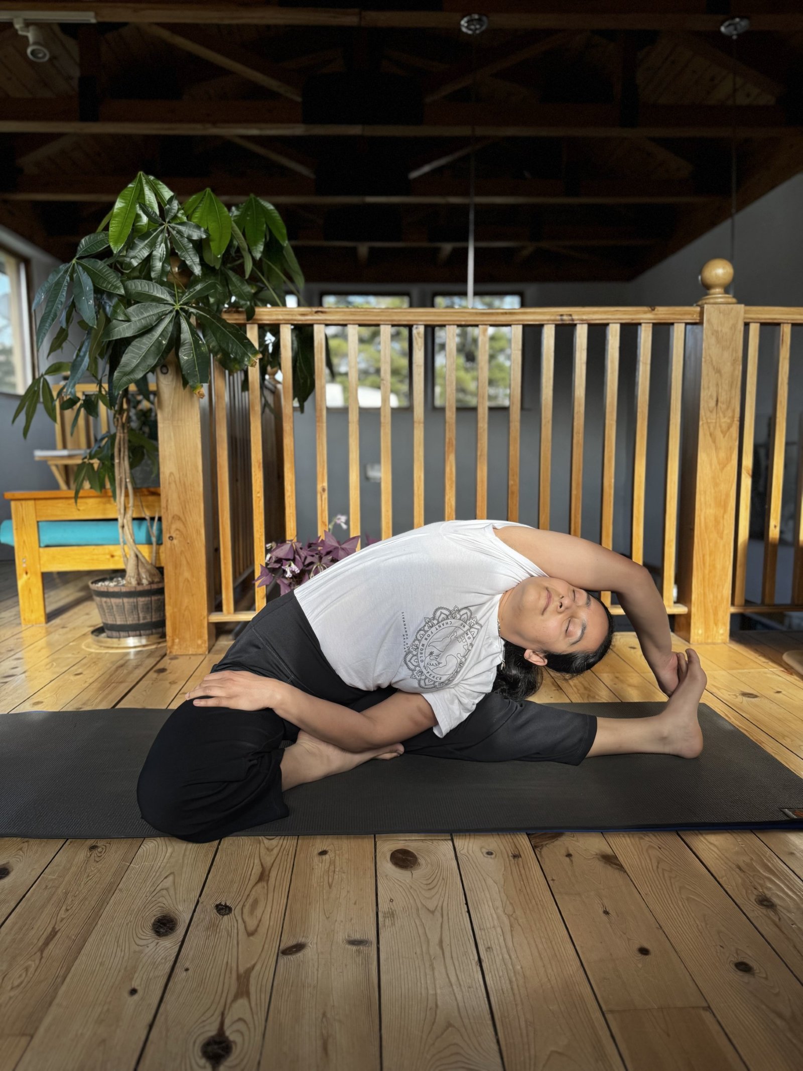 Purnima in a seated side stretch in a sunlit loft